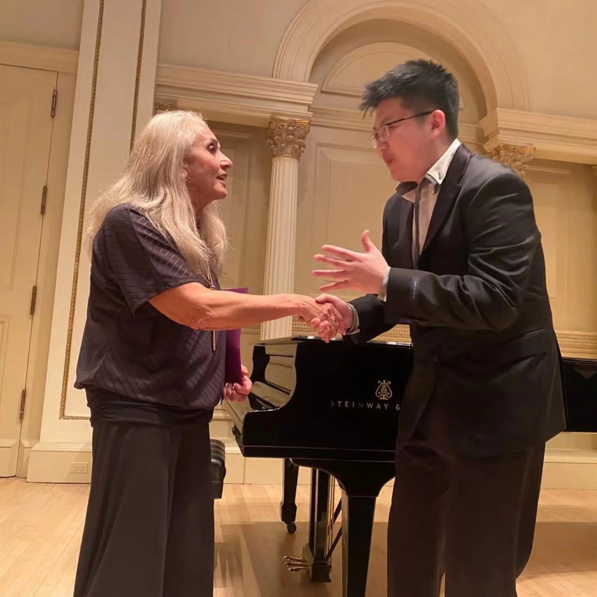 Xingyu Liu receiving a Steinway teaching award with a handshake